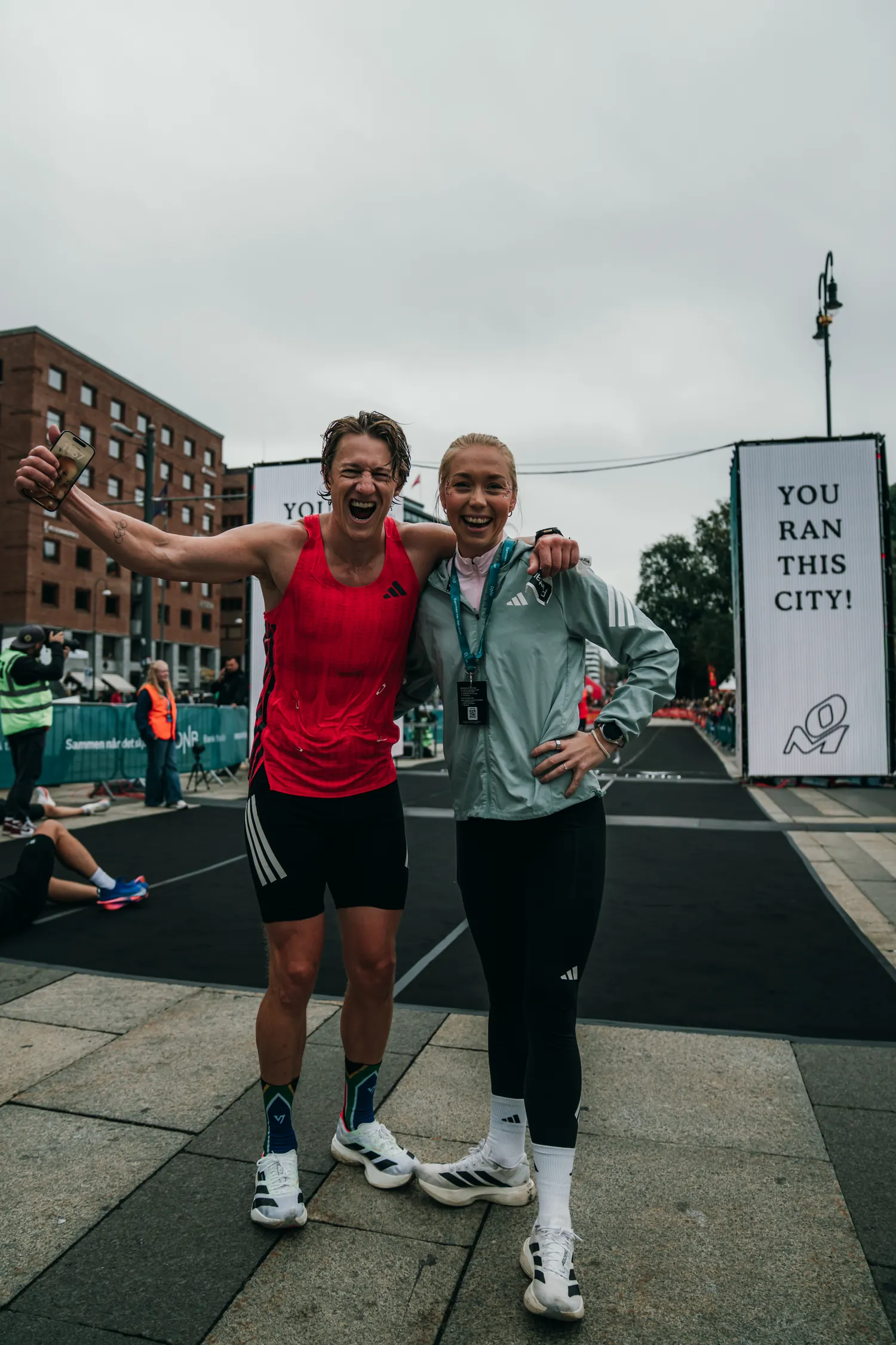 Matt Smith og løpecoach Veronica Undseth feirer foran skiltet «You ran this city!» etter Oslo Maraton 2026