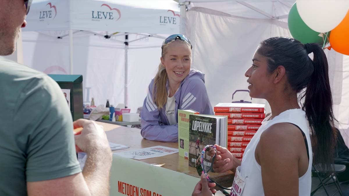 Løpecoach Veronica Undseth i samtale med en deltaker på standen under Jentemila på Bislett Stadion